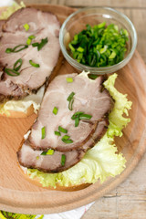 Appetizing sandwiches with meat, lettuce and sauce served with olives. Rustic style.