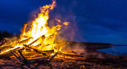 Fototapeta premium Big bonfire on the shore at night