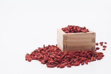 Dried red goji berries in the wooden square cup isolated