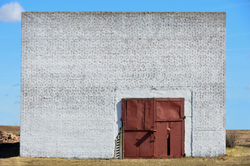 The wall of an abandoned brick building with large garage gates