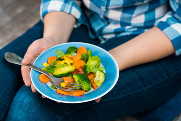 Girl with a plate of vegetables in hands