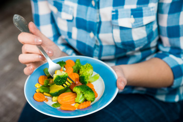 Girl with a plate of vegetables in hands