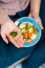 Girl with a plate of vegetables in hands. Healthy eating concept. Girl in jeans and a red shirt in a cage. Casual Style. Proper nutrition. Diet. Health. Vegetarian food. Vegans food.