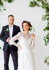 Bride with a branch in his hands poses near the groom.