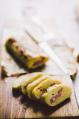 Roll made with smashed potatoes cheese and mortadella, on a wooden cutboard