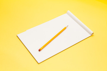 Sheet of cross lined office paper with yellow pencil on yellow background