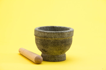 Stone mortar and pestle on yellow surface