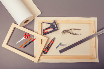 Canvas artist on roll, stretcher for canvas, staple gun and other tools on a gray background
