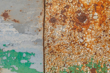 painted iron surface with a large rusty and metal corrosion, chipped paint, old background with peeling and cracking paint, texture