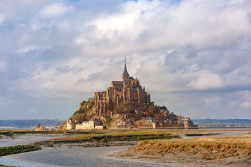 Fototapeta na wymiar Beautiful famous Mont Saint Michel at low tide in the cloudy morning, Normandy, France