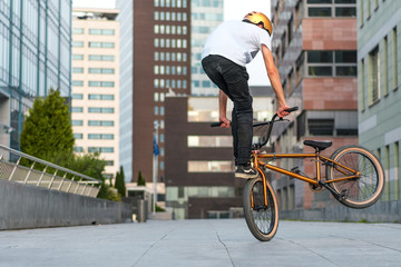 Young rider making trick on bmx bicycle in the street.