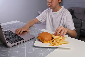 Children bad eating habits, Kid eating unhealthy junk food and playing computer games
