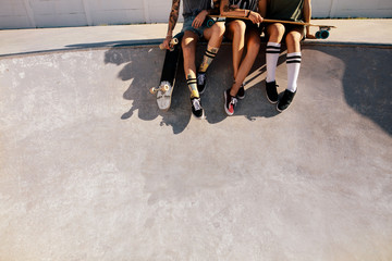 Legs of female skaters sitting together at skate park © Jacob Lund