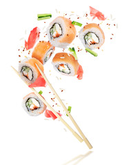 Pieces of fresh sushi with chopsticks frozen in the air, isolated on white background