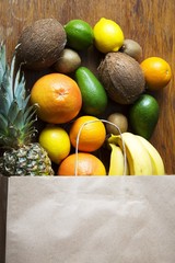 Paper bag of different fruits on wooden background. Flat lay. Top view.