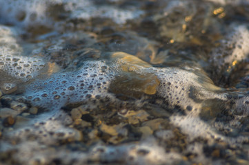 pebble stones on the sea beach, the rolling waves of the sea with foam