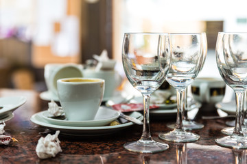 dirty and used glass plates, cups and glasses on a restaurant table
