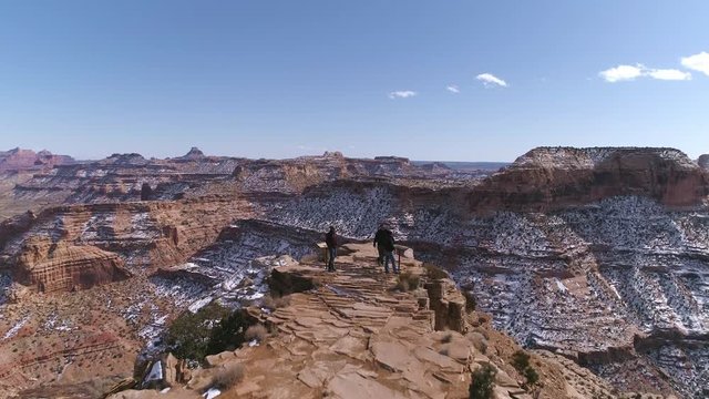 Aerial view flying over 3 people at a view point in the desert overlooking the Little Grand Canyon at the Wedge in the San Rafael Swell.