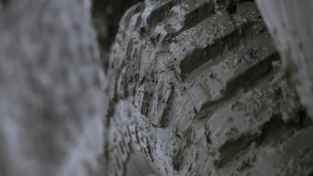 Zoom in and zoom out on off-road  muddy vehicle tire. Vehicle moves away.