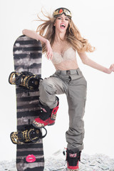 Snowboard girl. Winter, leisure, extreme sport and people concept - woman in ski goggles with very expressive emotion holds snowboard. Attractive athletic woman wears sexy clothes, standing on dollars