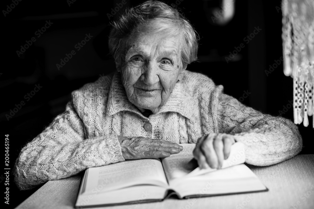 Wall mural Grandmother sitting read books at the table.