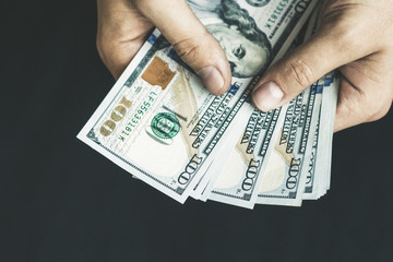 The white young man counts the money, one hundred new dollar bills on a black background close plan. Concepts of business and finance. top view .