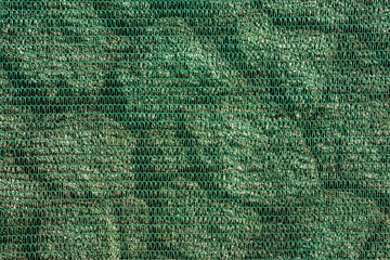 Texture of a stone wall covered with a protective green mesh