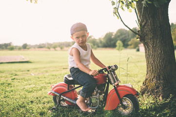 Young boy on red motorcycle making a face