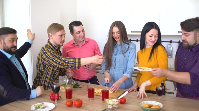 Friends laugh and joke while preparing buffet for casual dinner party. Happy group of friends having fun in a kitchen. 4 k