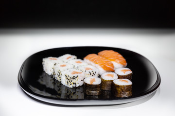 Sushi, Japanese food prepared with a base of rice and various raw fish. Here it is served with a particular and modern style, where the colors of the salmon stand out on the basis of black and white.