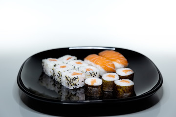 Sushi, Japanese food prepared with a base of rice and various raw fish. Here it is served with a particular and modern style, where the colors of the salmon stand out on the basis of black and white.