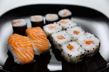 Sushi, Japanese food prepared with a base of rice and various raw fish. Here it is served with a particular and modern style, where the colors of the salmon stand out on the basis of black and white.