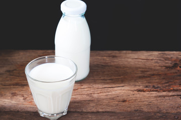 Fresh milk in drinking glass and two bottles on wooden table, Healthy concept