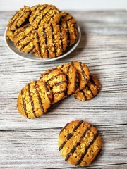 cookies poured with chocolate and pieces of peanuts is a slide on a white plate on a light table