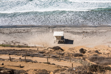 View from above of a lifeguard station and a dirt trail providing beach access at Beacon's Beach in Encinitas, California.