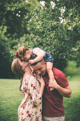Mother kissing daughter on daddy's shoulders