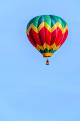 balloon with a basket and a flame from a burner, hovers in a blue sky