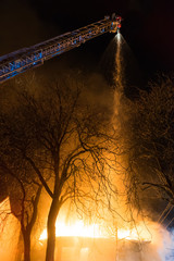 Strong and brave firefighters spraying water on burning building house