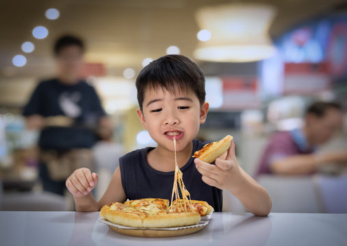 Asian Boy Is Happy To Eat Pizza With A Hot Cheese Melt Stretched On A Wooden Pad