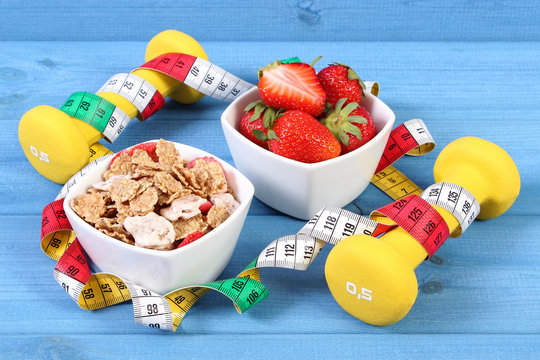 Fresh strawberries, wheat and rye flakes, dumbbells and centimeter, concept of healthy and sporty lifestyle