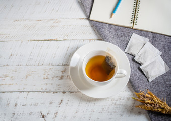 A cup of hot herbal tea on white wooden table.