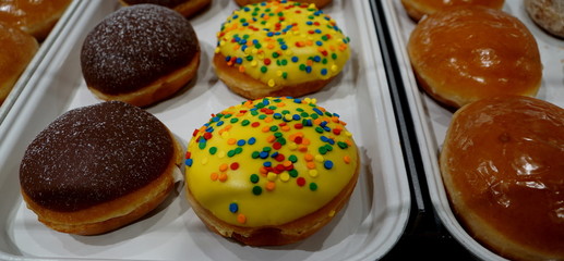 Yellow and colorful donuts on white tray.