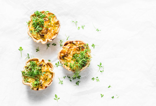 Mini savory pie with chicken, leek, cheese on light background, top view. Delicious appetizer, snack, breakfast, tapas
