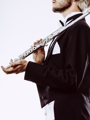 Male flutist wearing tailcoat holds flute