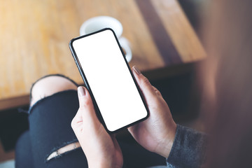 Mockup image of woman's hand holding black mobile phone with blank white desktop screen in cafe