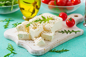 Feta cheese, cherry tomatoes and rucola on the table. Ingredients for salad.