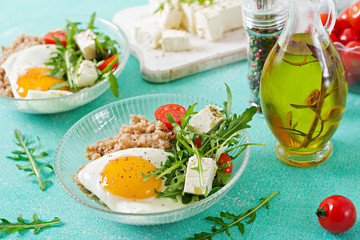 Healthy breakfast with egg, feta cheese, arugula, tomatoes  and buckwheat porridge on light background. Proper nutrition. Dietary menu.