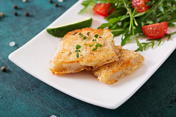 Fried white fish fillets and tomato salad with arugula.