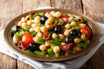 Delicious homemade salad balela with chickpeas, tomatoes, onions, olives and herbs closeup. horizontal, rustic