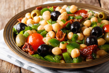 Vegan salad baleola with chickpeas, tomatoes, onions, olives and herbs close-up. horizontal